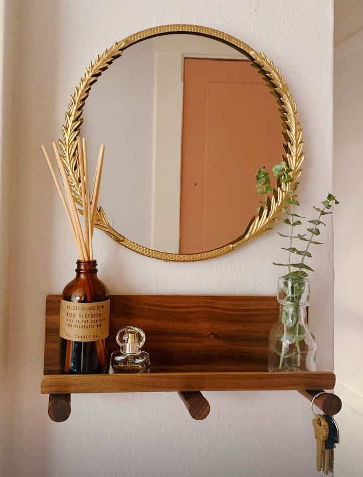 Minimal entrance space with warm wood tones and golden round mirror