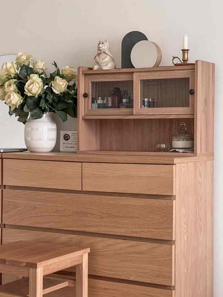 Warm wood tone bedroom featuring a dresser with cabinet adorned with a vase and decor items