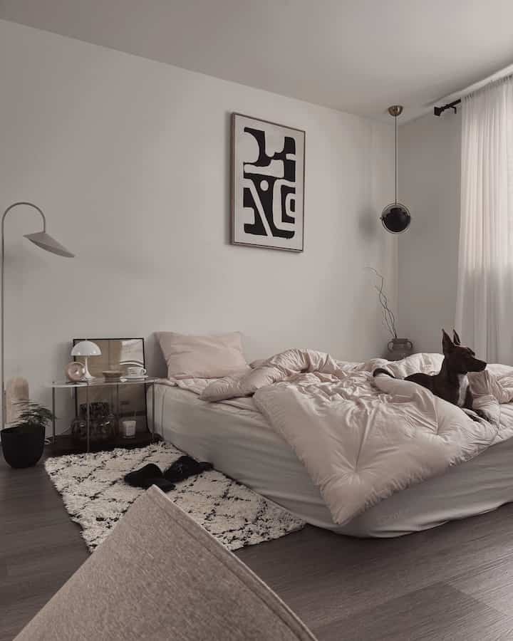 Cozy bedroom in soft beige and white tones featuring a bed with a dog resting on the duvet