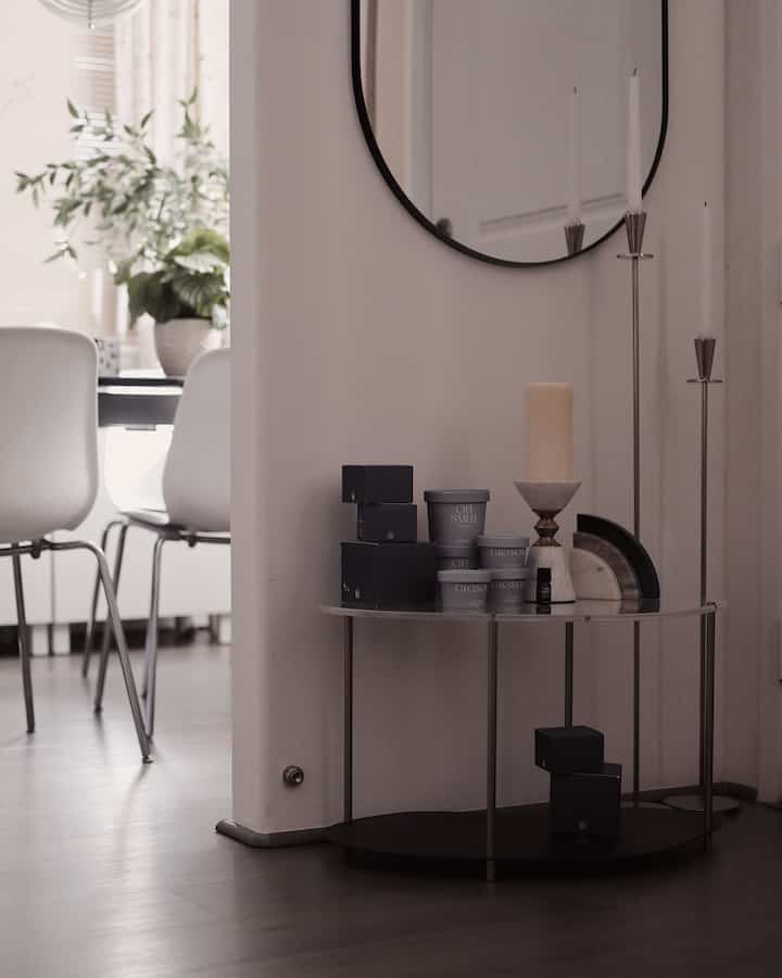 Modern entrance space in white and gray tones featuring a side table with candleholders and decor creating a minimalist atmosphere