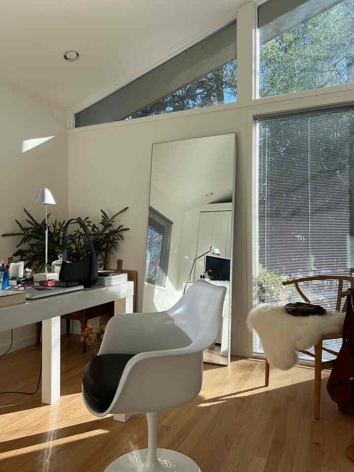 Bright white and wood tone home office featuring large windows, desk, and office chair with natural, cozy atmosphere