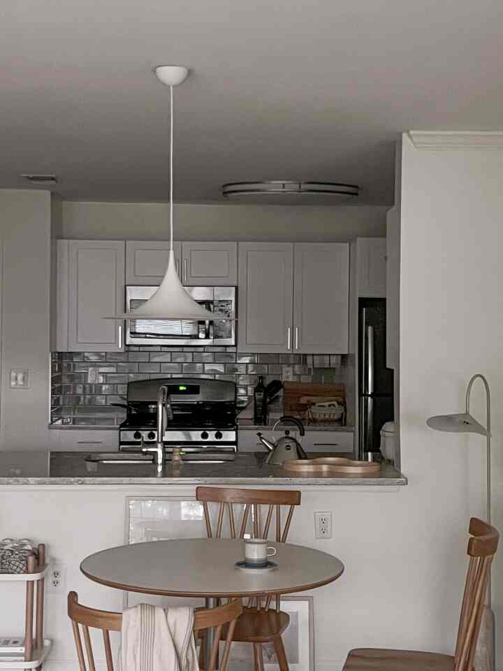 White-toned dining room combined with kitchen featuring round dining table and pendant light creating a cozy atmosphere