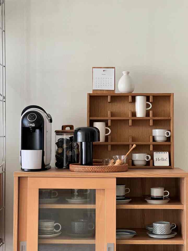 Natural wood tone home cafe space featuring coffee machine and cups neatly arranged for cozy ambiance
