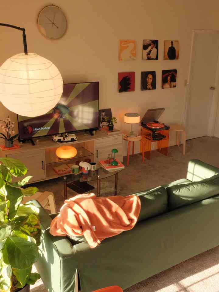 Warm orange and green toned living room featuring sofa and record player with retro vibe