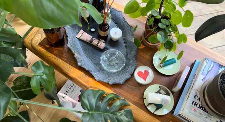 Natural wood tone bedroom table featuring green plants and various decorative items creating a cozy atmosphere
