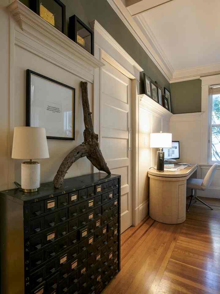 Natural tones and black accents define a home office space featuring a desk and table lamps, creating a cozy working environment