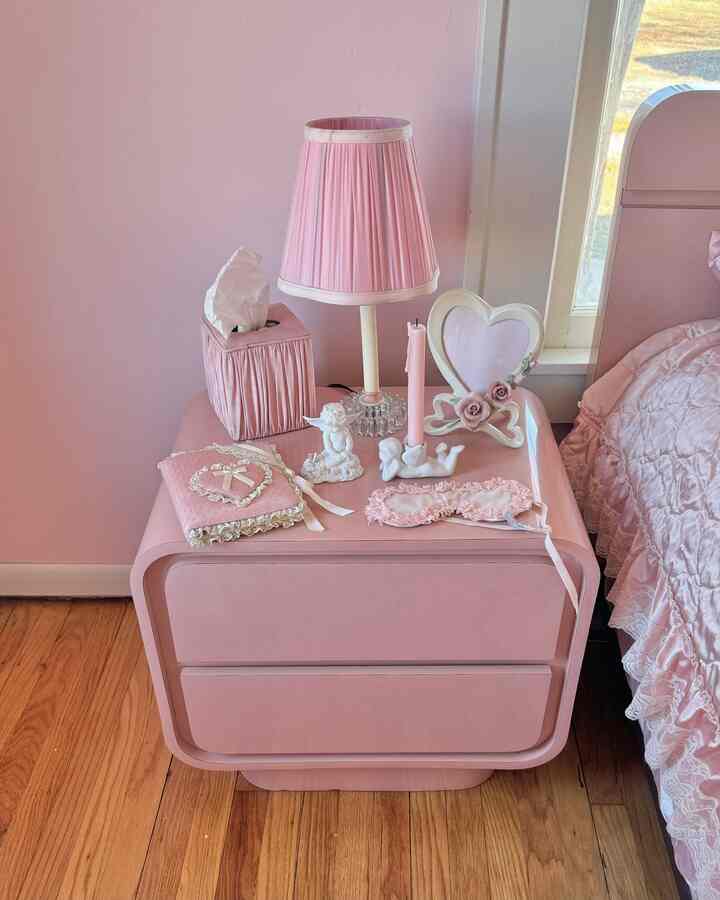 Soft pink-toned bedroom featuring a pink nightstand and lace bedspread with a vintage atmosphere