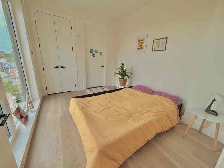 Modern bedroom with white walls, yellow duvet cover on bed, side table, and plant creating a cozy atmosphere