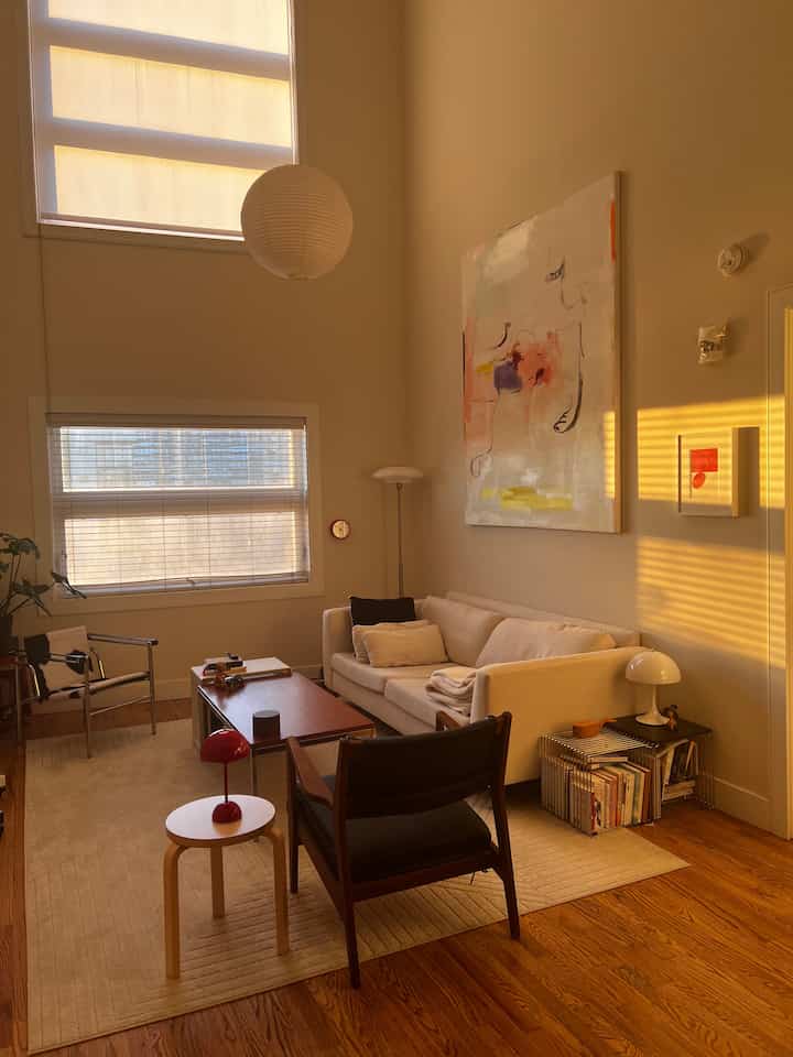 Warm beige and wood tone living room featuring minimalist sofa, stools, and table lamps, creating a cozy atmosphere