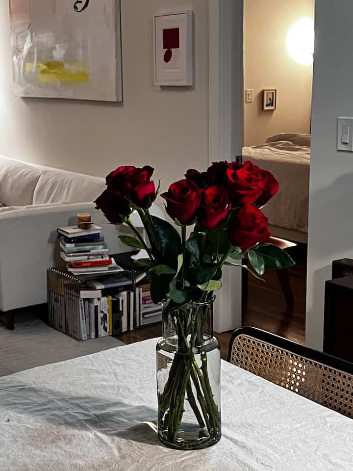 Warm white-toned dining room featuring vibrant red roses in a vase, creating a cozy natural modern atmosphere