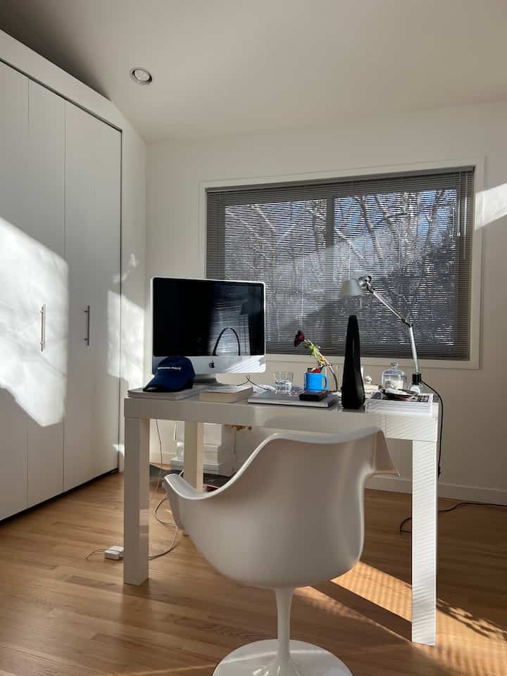 Bright white and wood tone home office featuring a central desk and chair with a clean and airy workspace