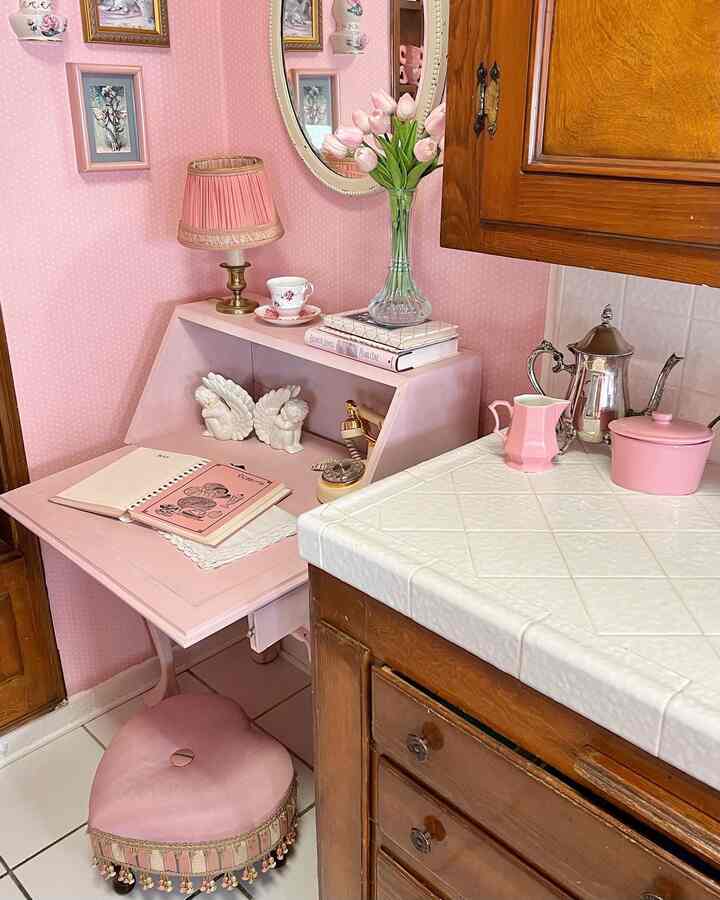 Pink-toned wallpapered kitchen space featuring a vintage-style desk with romantic and warm atmosphere