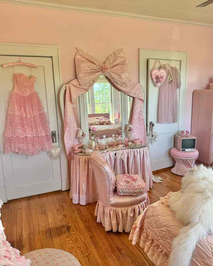 Pink-toned bedroom featuring bow-adorned vanity and ruffled armchair in a vintage-inspired setting