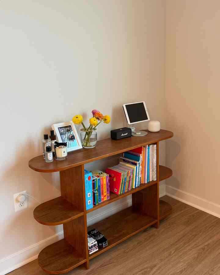 Natural brown toned living room bookshelf with vase, diffuser, and candle creating a cozy atmosphere