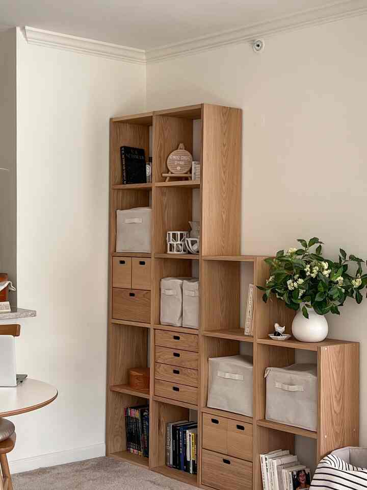 Living room with white walls featuring natural wood tone shelving, neatly organized storage boxes, and a clean, natural atmosphere