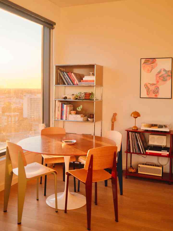 Warm beige and wood tone dining room featuring a round dining table, chairs, and bookshelf in a cozy atmosphere