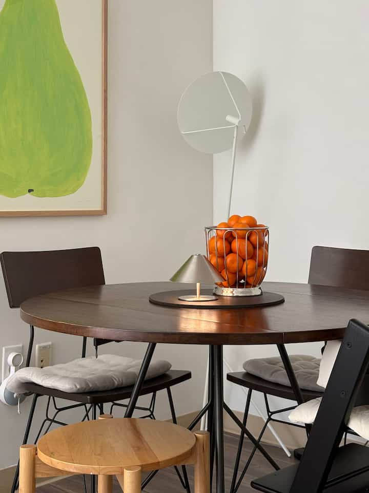 Bright white walls with dark wood tone dining table and basket of orange fruits in a mid-century modern dining room