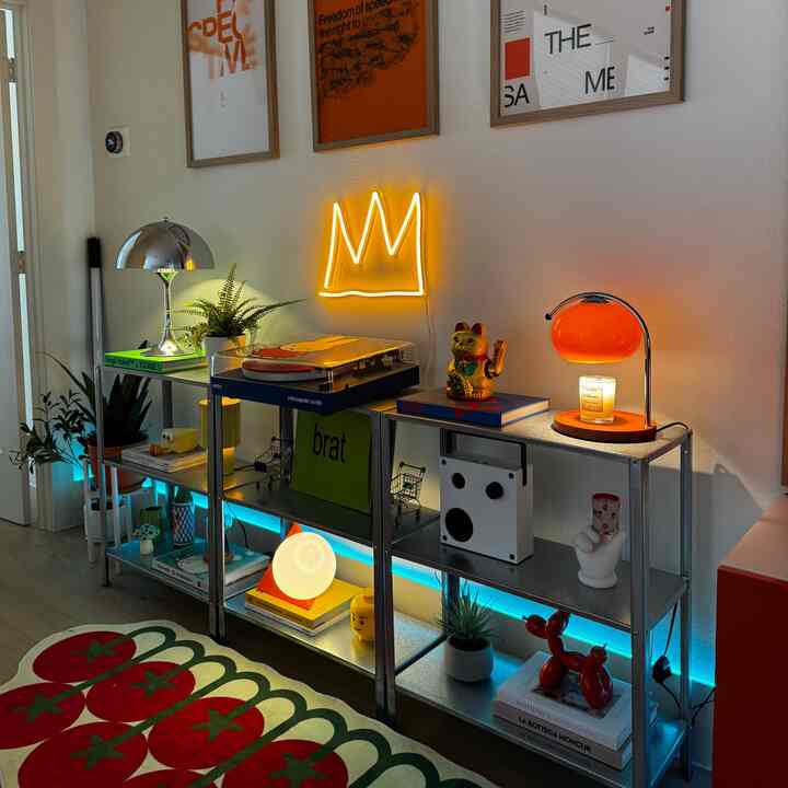 Retro style living room with orange neon sign, vintage turntable, and various decorative items on metal shelving