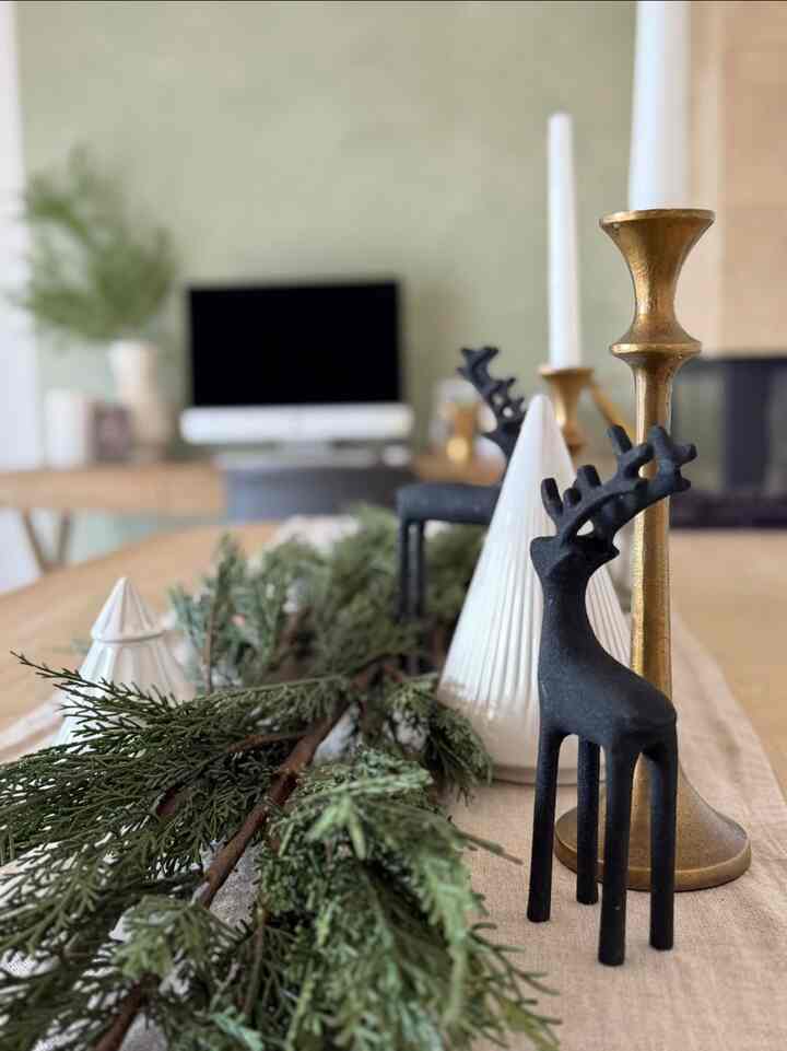 Natural wood tone dining room with gold candle holders and black deer figurines arranged on the table, creating a warm and cozy atmosphere