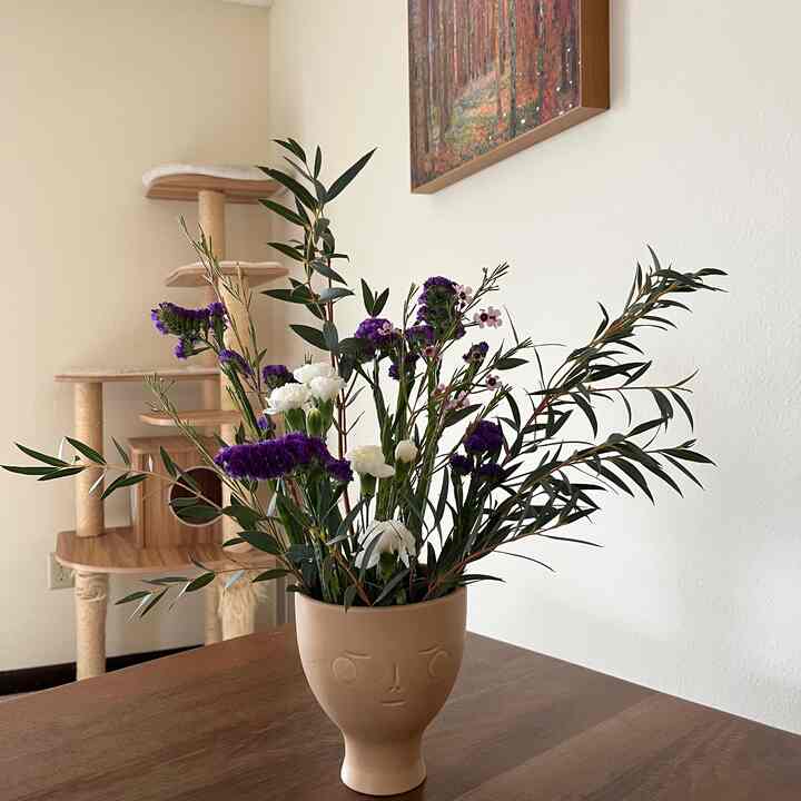 Beige and wood-tone living room with a face-design vase holding flowers, creating a natural and cozy atmosphere