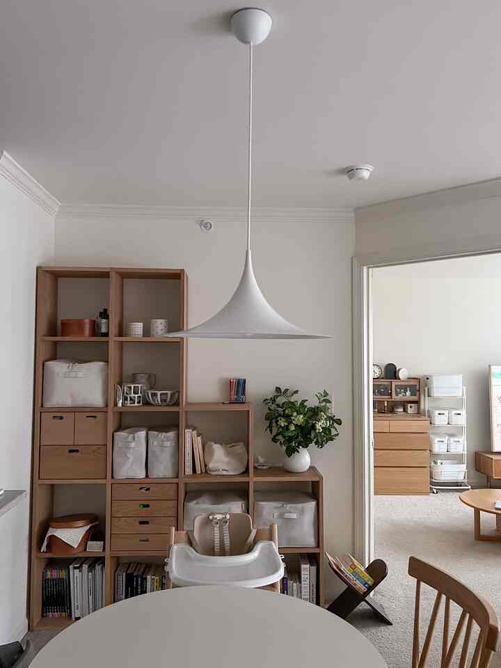 Beige and wood tone living and dining room with pendant light and neatly arranged storage furniture, embodying a natural modern style