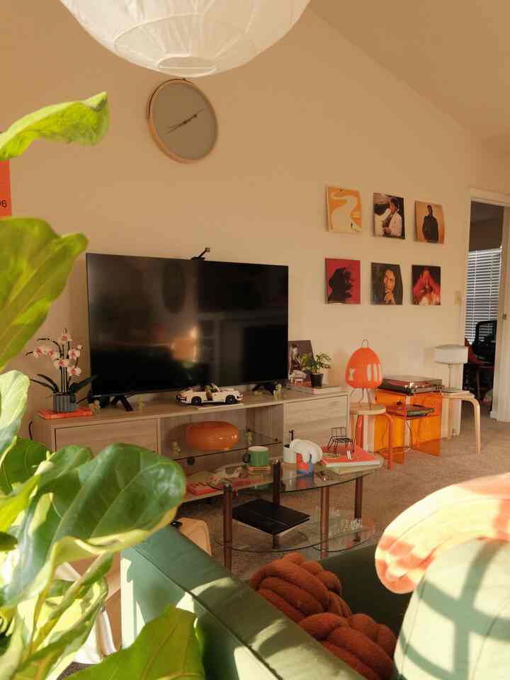 Living room with green sofa and orange lighting accents, featuring plants adding a natural touch