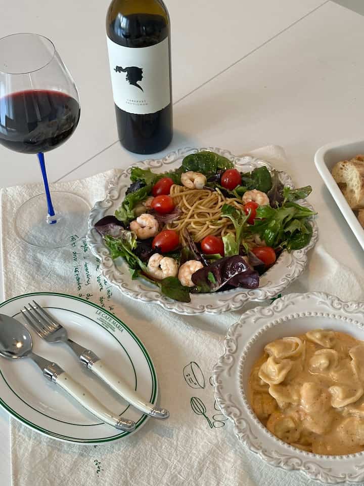 A white table featuring vintage plates and a wine glass in a French Country style home cafe dining setting