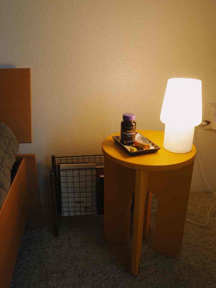 Cozy bedroom nightstand featuring a yellow side table with a white table lamp and organized tray