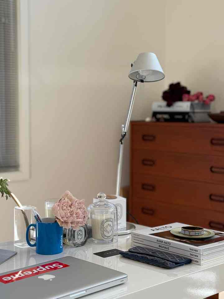 White and wood tone home office featuring an Artemide table lamp and desk, creating a simple and modern atmosphere