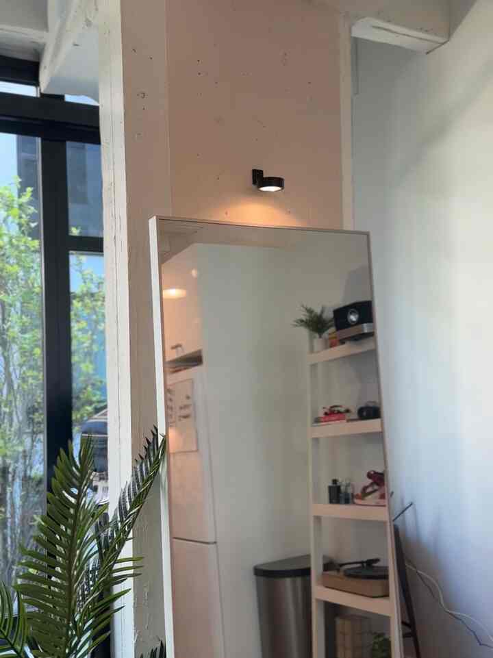 Minimal living room corner with white walls, a large mirror, and a spotlight illuminating the area neatly