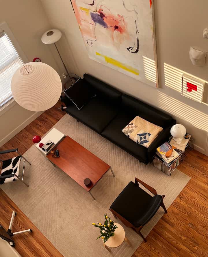Wood tone floor and beige rug in a living room featuring black sofa, armchair, table lamps, and a floor lamp with cozy atmosphere