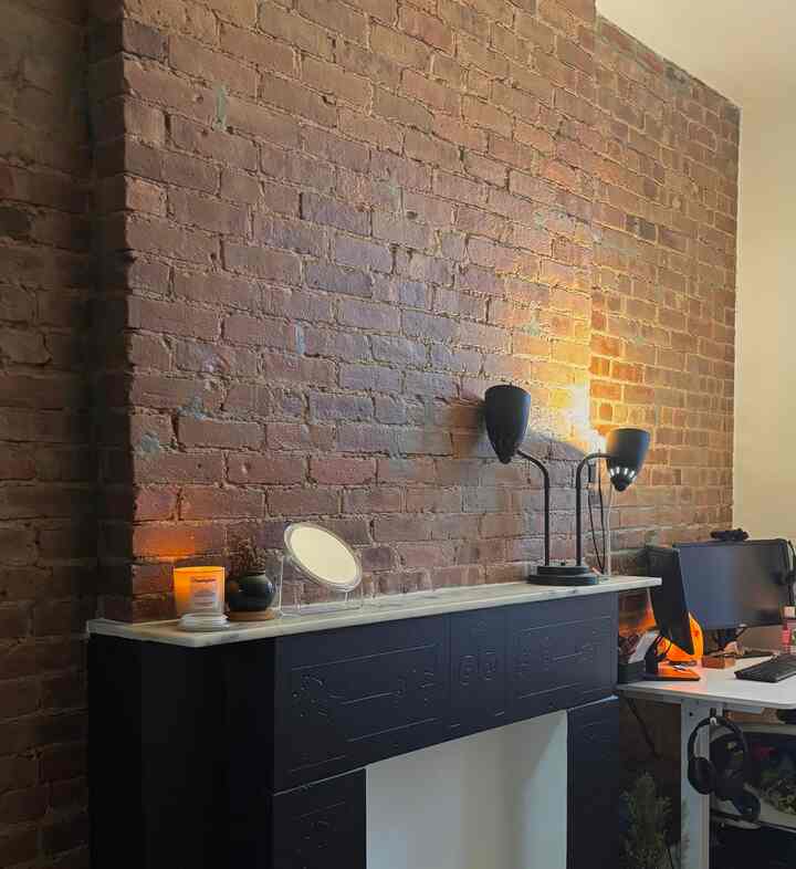 Brown-toned exposed brick wall home office featuring black furniture and lighting elements with a modern atmosphere