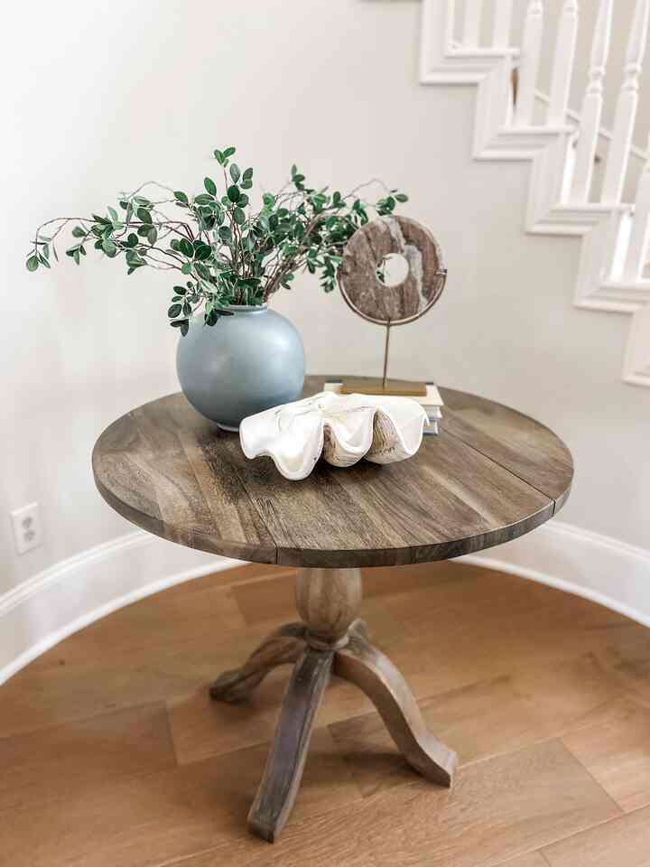 Natural color wood tone round entrance featuring a wooden dining table with a blue vase and decorative objets in a simple style