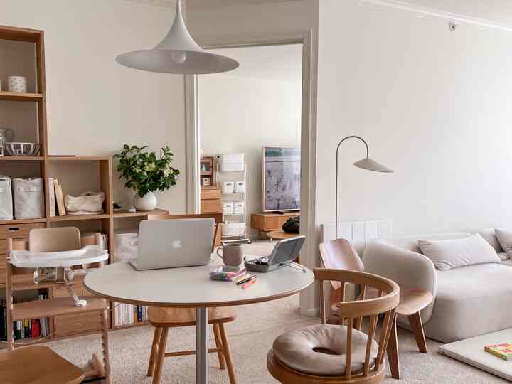 Beige and wood tone living room home office featuring round table, organized shelves, and a natural atmosphere