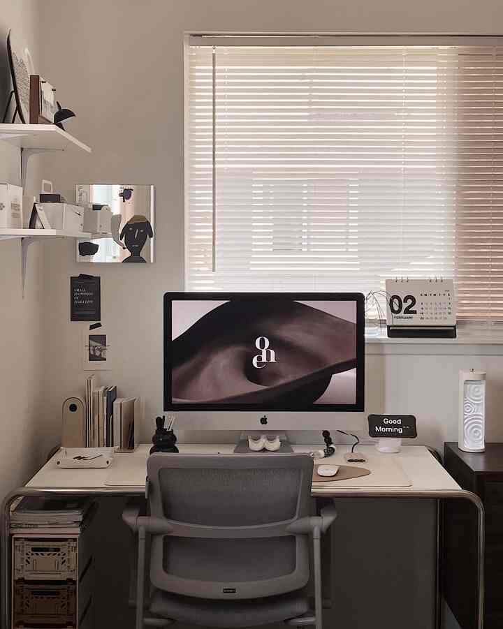 Small home office in white and gray tones featuring an iMac, desk, and office chair with a clean workspace atmosphere