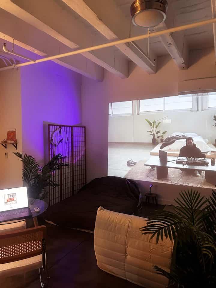 Natural-toned compact single household home office and bedroom space featuring plants and cozy furnishings