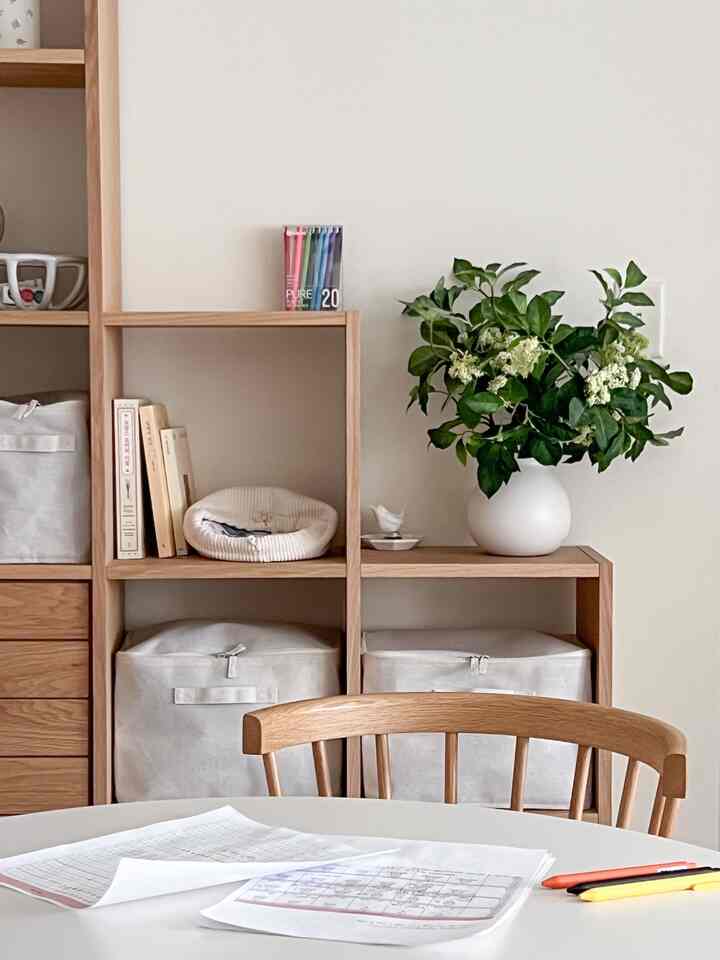 Wood tone and beige home office space featuring organized shelving and dining chairs with a calm atmosphere