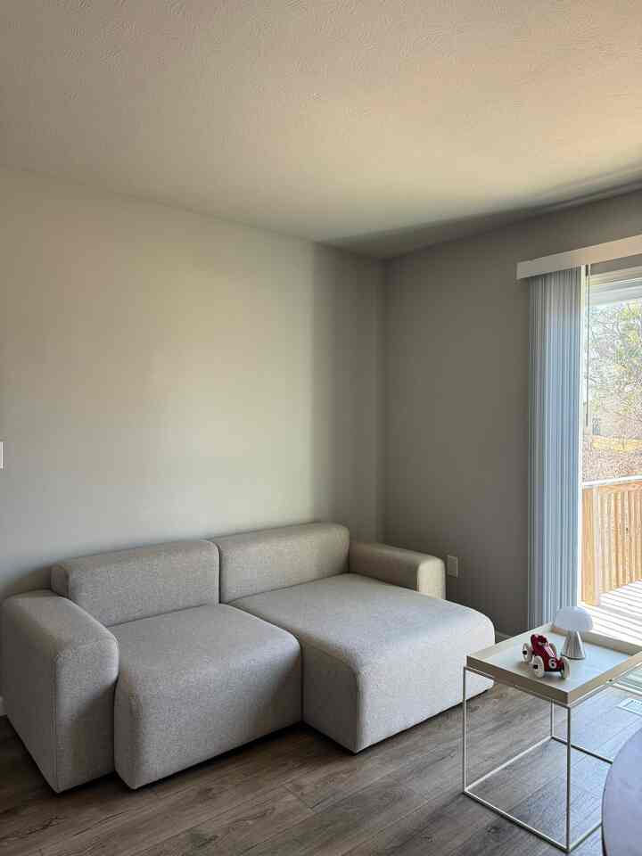Natural and wood tone living room featuring a modern, minimal gray sectional sofa and small side table