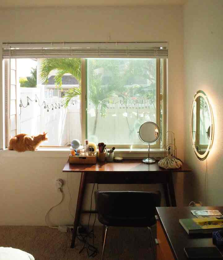 Natural-light filled powder room featuring round lighted mirror and organized vanity with natural tones