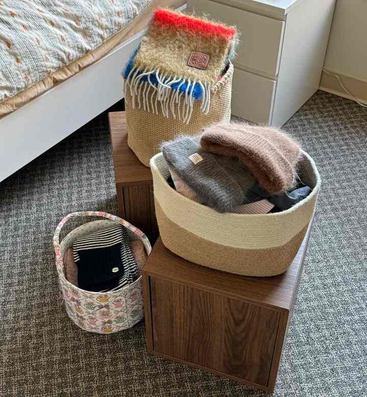 Beige and brown toned bedroom featuring various fabric storage bins and a cabinet arranged for organizing winter clothes