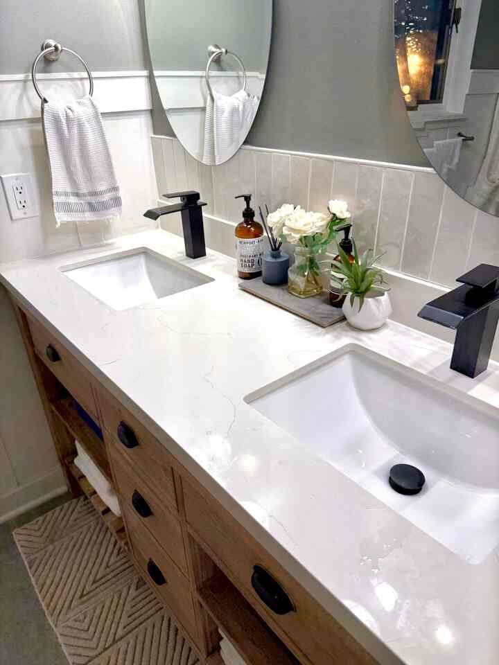 Modern bathroom in white and black tones featuring a wood-tone vanity with double sinks and clean aesthetic