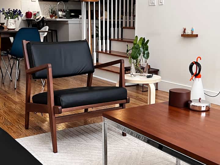 Natural modern living room corner with brown wood tones and black leather armchair