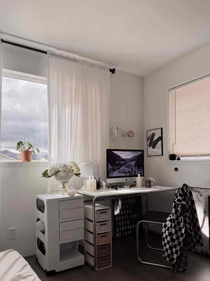 White modern home office featuring a clean desk with iMac and vase of flowers, creating a bright and orderly workspace
