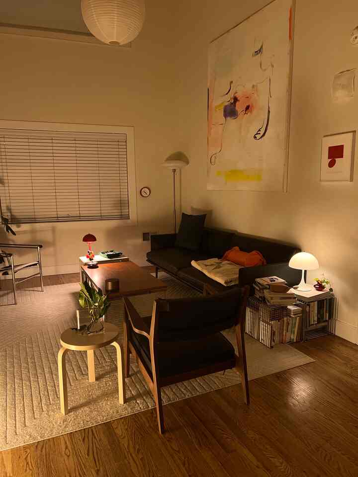 A cozy mid-century modern living room with warm wood tones and white walls, featuring a sofa and table lamps