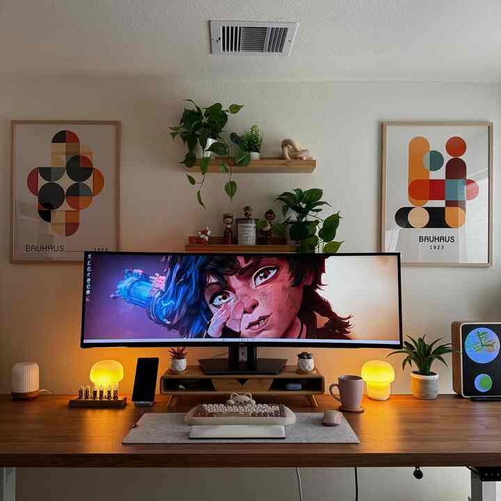 Natural wood tone minimal home office featuring a large curved monitor and cozy lighting creating a comfortable workspace