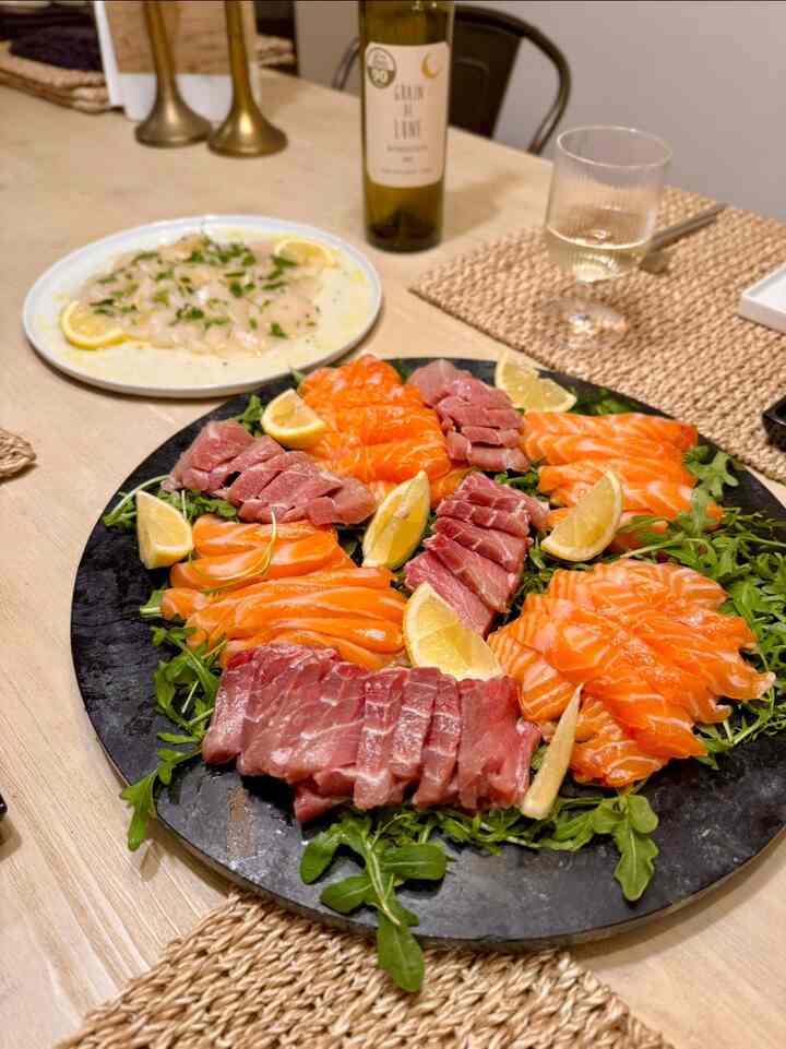 Natural wood-toned dining room featuring a natural dining table with modern plates set with vibrant sashimi and wine glass