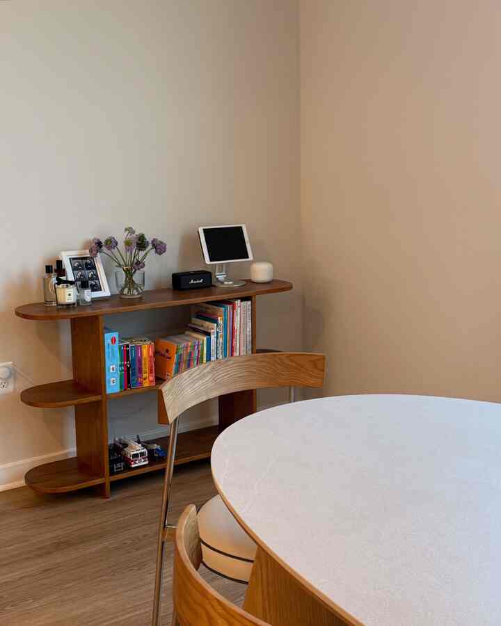Natural color walls and wood tone dining table with vase and bookshelf placed in a cozy living room