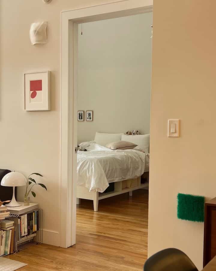 Mid-century modern bedroom with natural wood tone floor and white bed creating cozy atmosphere