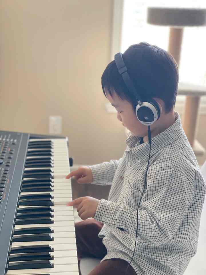 Natural beige toned kids' room featuring a child playing keyboard with headphones in a minimal setup