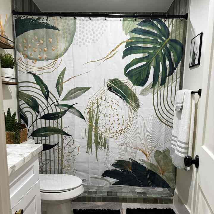 White and green toned bathroom featuring plants and botanical shower curtain with a natural and cozy atmosphere